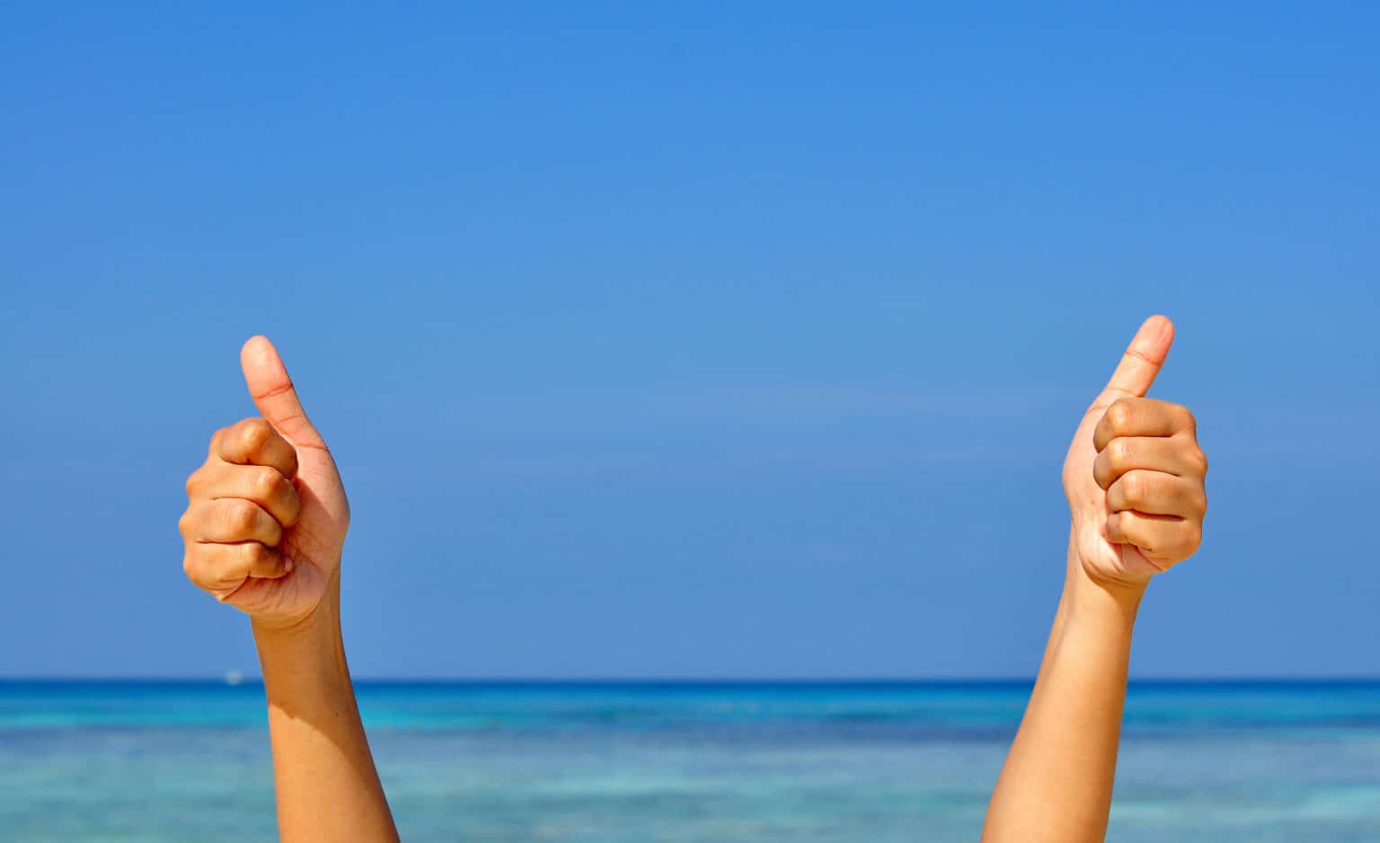 Two hands with thumb up on blue sky and sea background